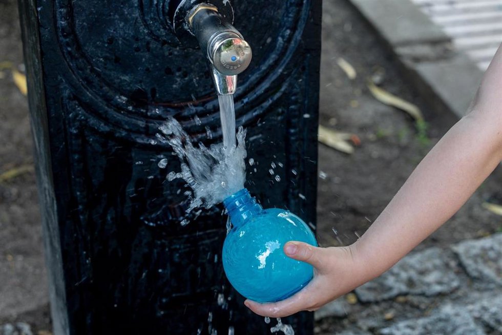 Archivo - Una persona llena un bote de agua en una fuente.