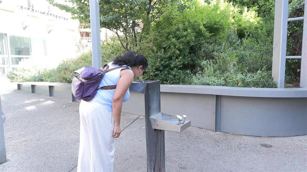 Mujer refrescandose y bebiendo agua en una imagen de archivo