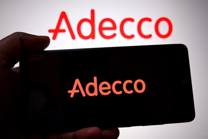 Archivo - February 23, 2026, India: In this photo illustration, an Adecco logo is seen displayed on a smartphone and in the background.
