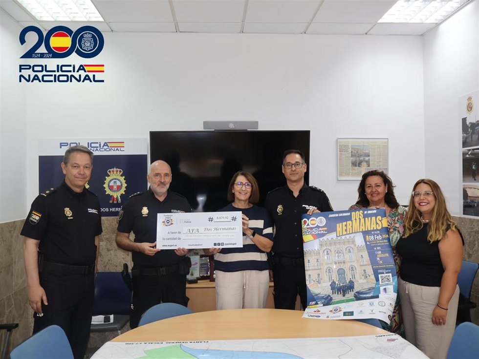 Representantes de la Policía Nacional de Dos Hermanas y la Asociación de Familiares de Enfermos de Alzheimer y otras Demencias (AFA) durante la entrega del cheque.