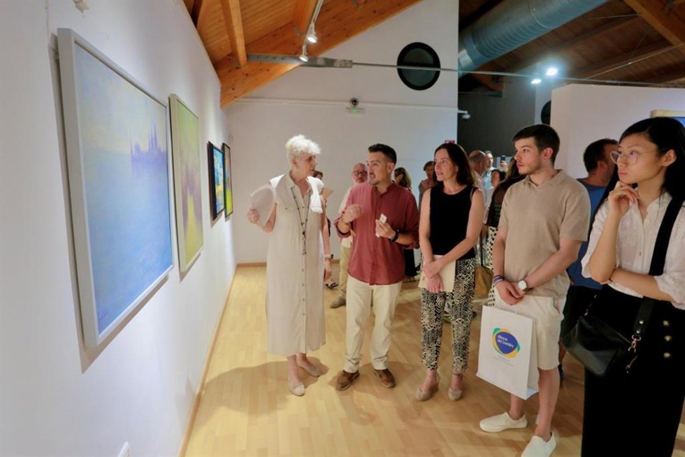El delegado de Cultura de Alcalá de Guadaíra (Sevilla), Christopher Rivas, y visitantes del Museo de Alcalá contemplan un paisaje de la exposición 'El paisaje. Miradas contemporáneas'