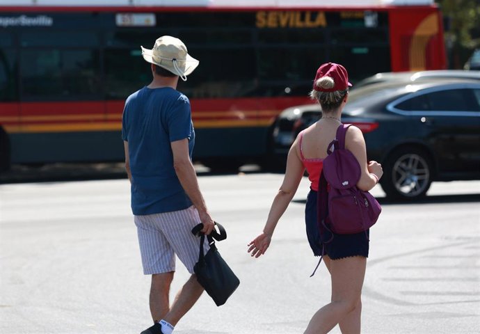 Varias personas se protegen del sol con sombreros. 