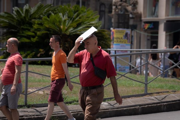 Archivo - Arxivo - Una persona tracta de protegir-se del sol en Les Rambles, a 18 de juliol de 2023, a Barcelona, Catalunya (Espanya). 
