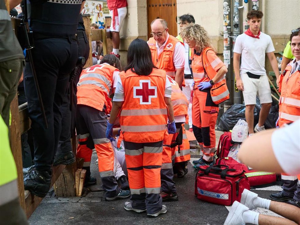 Voluntarios Cruz Roja atienden a un corredor herido en el sexto encierro de los Sanfermines de 2026, protagonizado por toros de la ganadería La Palmosilla.