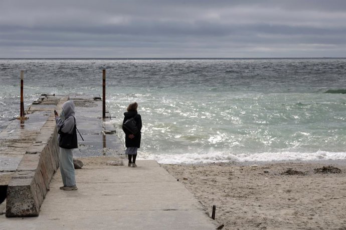 Archivo - Arquivo - 12 de maio de 2026, Odessa, Ucrânia: Pessoas estão na orla da Praia de Langeron; manchas de óleo são visíveis na água. No final de abril, a Rússia perfurou tanques de armazenamento de óleo vegetal próximos a Odessa, o que resultou no d