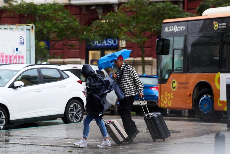 Archivo - Varias personas se cubren de la lluvia y el viento con paragua en Santander.-ARCHIVO