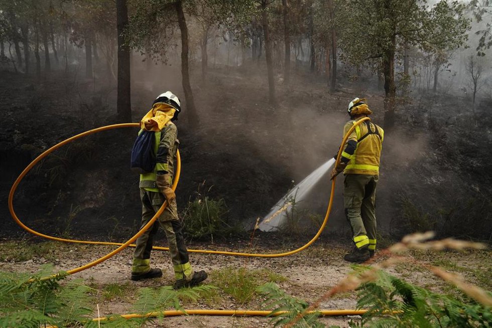 Dos bomberos forestales tratan de extinguir un incendio, a 13 de junio de 2026, en Padrón, A Coruña, Galicia (España).