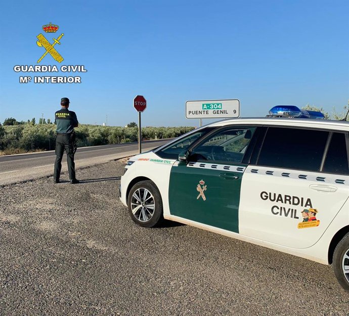 Archivo - Un guardia civil, junto a su vehículo, en uno de los accesos a Puente Genil.
