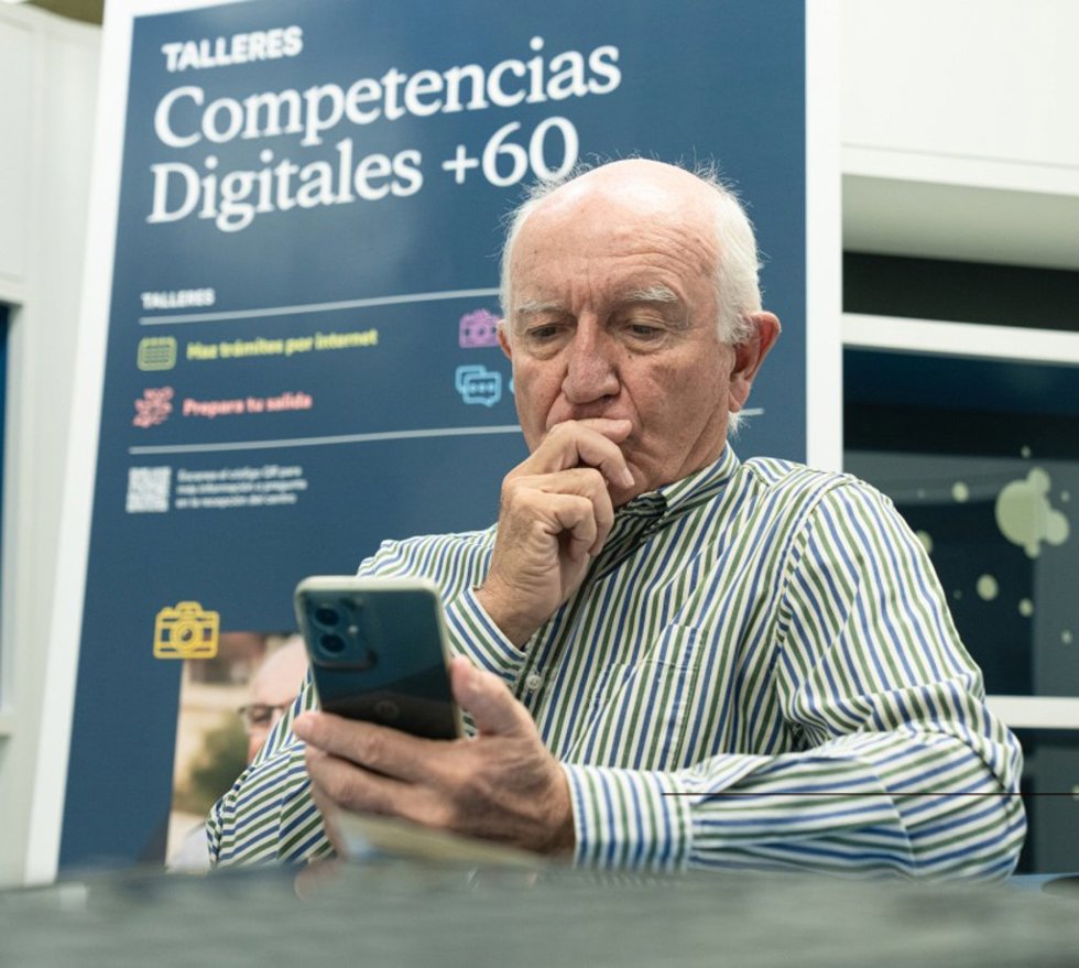 Un señor practica con el móvil durante los talleres Competencias Digitales +60