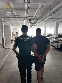 Agente de la Guardia Civil con uno de los detenidos.