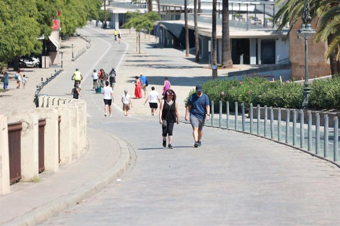 Archivo - Varias personas se protegen del sol con sombreros en Sevilla.