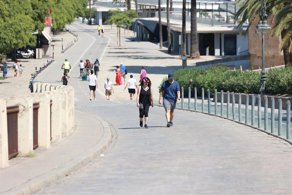 Archivo - Varias personas se protegen del sol con sombreros en Sevilla.