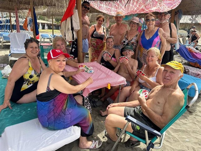 Un grupo de personas mayores disfrutan de un día de playa.