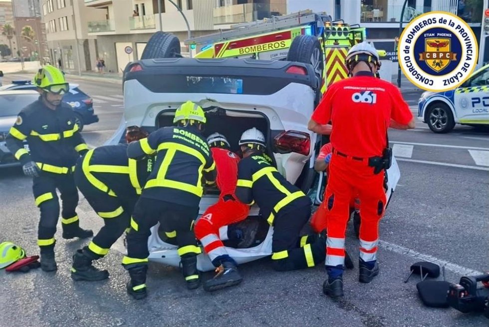 Efectivos de bomberos y 061 asistiendo a la mujer herida tras volcar el coche en Cádiz.