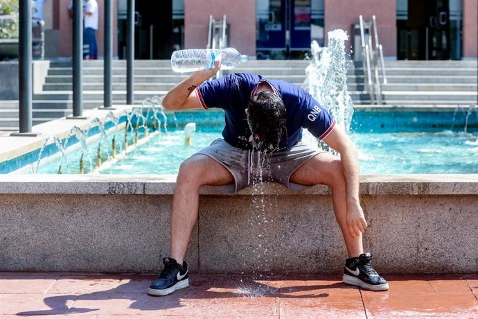 Archivo - Un joven se tira una botella de agua por encima para combatir la ola de calor 