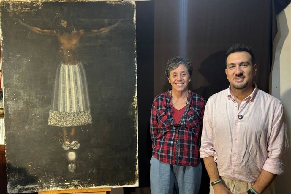El delegado de Cultura de Alcalá de Guadaíra (Sevilla), Christopher Rivas, y la restauradora Victoria Fernández, posan junto al Santísimo Cristo de Burgos de la Parroquia de San Sebastián