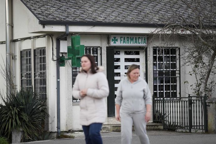 Archivo - Dos personas salen de una farmacia en una zona rural.