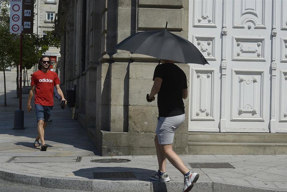 Archivo - Dos personas caminan por una vía en plena ola de calor