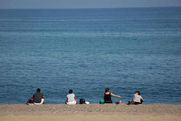 Archivo - Arxivo - Diverses persones assegudes a la Platja de la Barceloneta, en una imatge d'arxiu