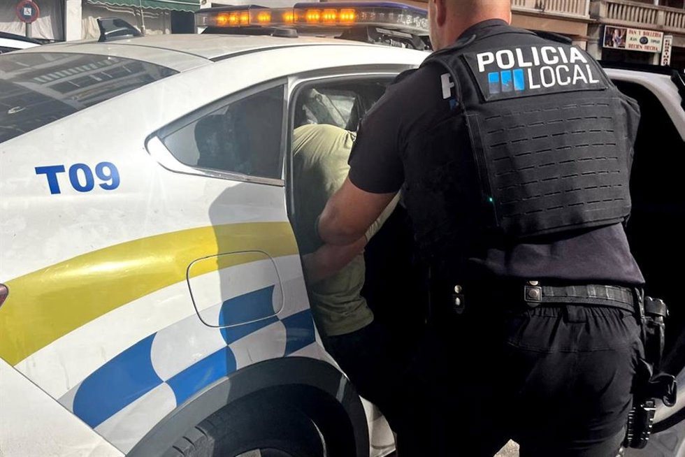 Un policía introduce a uno de los detenidos en un coche patrulla.