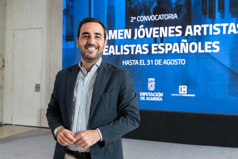 El diputado de Presidencia y Promoción de la Provincia de Almería, Carlos Sánchez, ante el cartel de la segunda convocatoria del Certamen de Jóvenes Artistas Realistas Españoles.