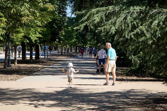 Archivo - Una persona junto a un niño en el parque de El Retiro. 