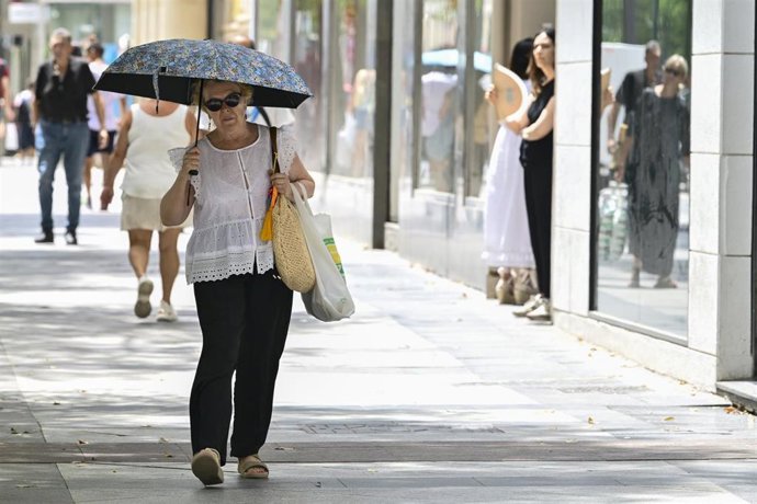 Una mujer se protege del sol con un paraguas durante una jornada de altas temperaturas.