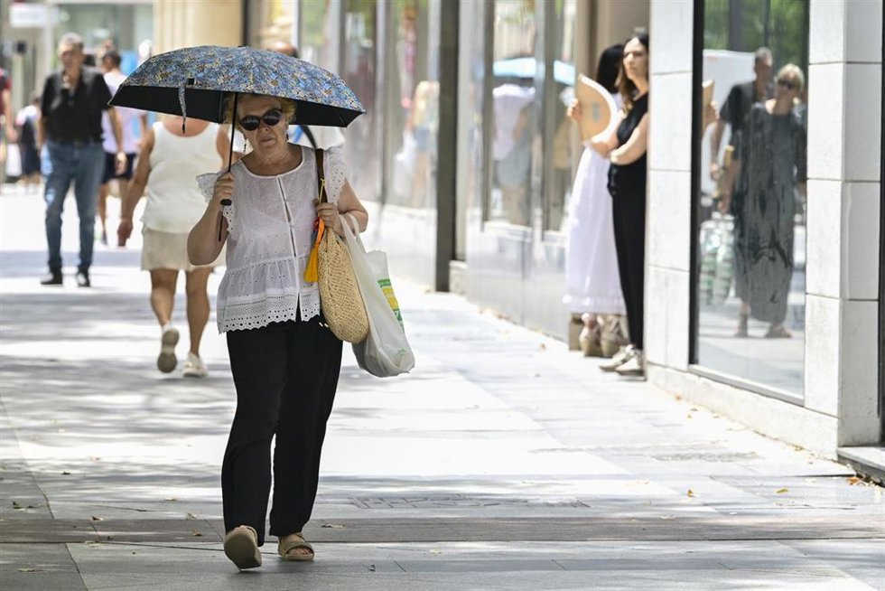 Una mujer se protege del sol con un paraguas durante una jornada de altas temperaturas.