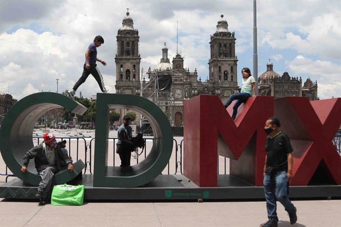 Archivo - 14 August 2021, Mexico, Mexico City: People sit on an installation reading "CDMX" (Mexico City) at Zocalo Plaza in Mexico City