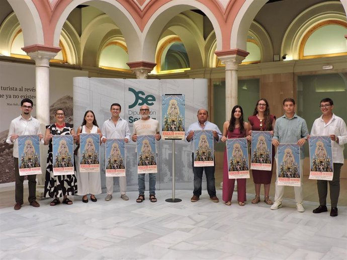 Vecinos de Benacazón sujetan el cartel de las fiestas patronales 'Las Nieves 2026' en la Casa de la Provincia de la Diputación de Sevilla.