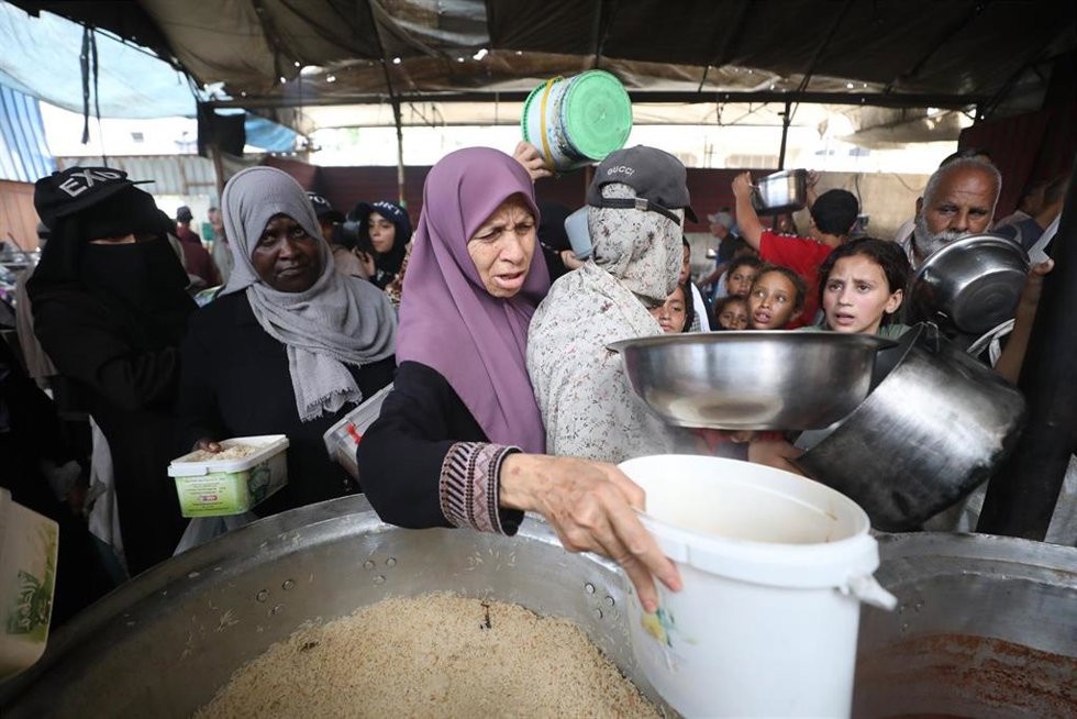 Los palestinos desplazados se reúnen para recibir comida de la única cocina benéfica que queda en el campo de refugiados de Nuseirat.