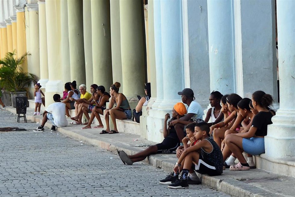 La gente se sienta a la sombra para protegerse del intenso calor durante un apagón generalizado en La Habana, capital de Cuba.