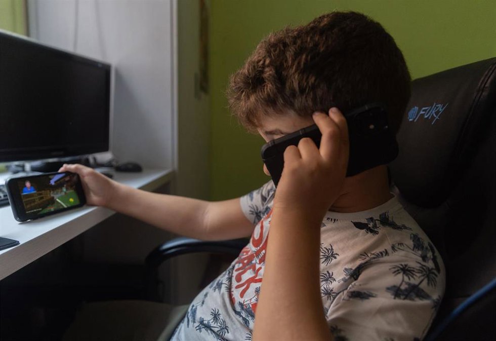 Archivo - Un niño conectado a varios dispositivos móviles sin supervisión.