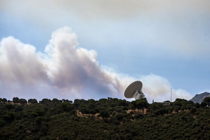 El humo de un fuego cercano sobrevuela una antena de la NASA, a 24 de julio de 2026, en Robledo de Chavela, Madrid (España).