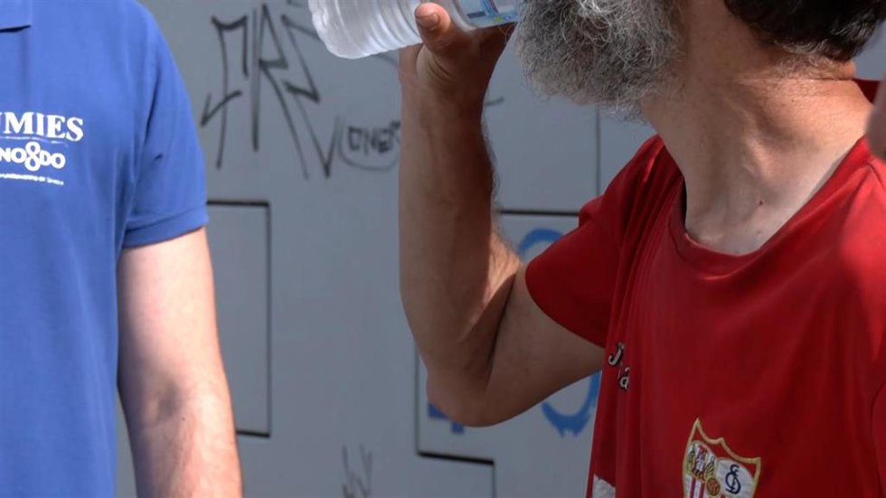 Archivo - Un trabajador social de la UMIES reparte agua a una persona sin hogar como imagen de recurso