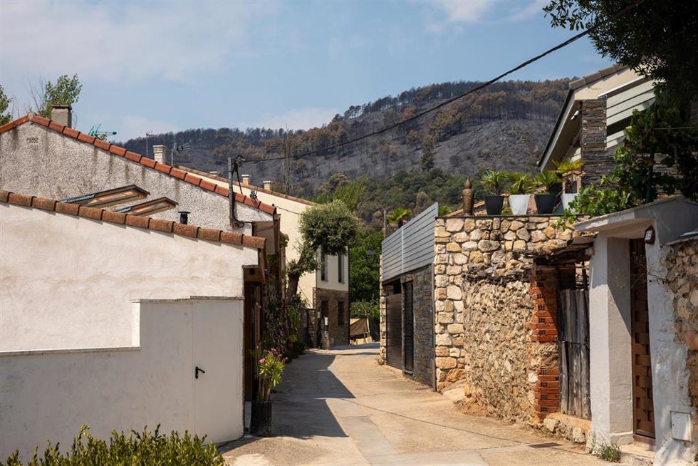Vista del pueblo con el terreno quemado por el incendio forestal al fondo, a 23 de julio de 2026, en La Mierla, Guadalajara, Castilla-La Mancha (España). Según fuentes del gobierno regional, el fuego de La Mierla, que cumple su primera semana activo y que