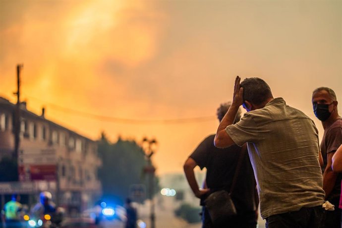 Varias personas observan el fuego durante las labores de extinción del incendio forestal, a 25 de julio de 2026, en La Adrada, Ávila, Castilla y León (España). La Adrada, uno de los municipios del Valle del Tiétar (Ávila), ha sido evacuado de forma preven