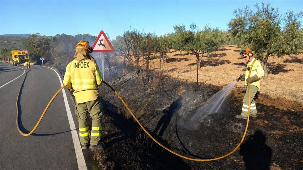 Archivo - Dos bomberos forestales del Infoex apagan un fuego junto a una carretera.