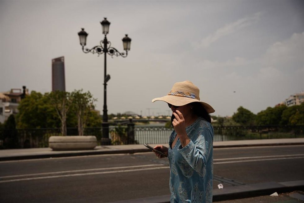 Archivo - Una mujer se protege del sol con un sombrero en Sevilla.