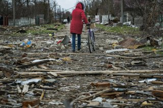 Archivo - April 11, 2022, Chernihiv, Chernihiv, Ukraine: A woman passes with her bicycle over the debris of the destroyed houses by russian shelling in Novoselivka, a village near Chernihiv, Ukraine.