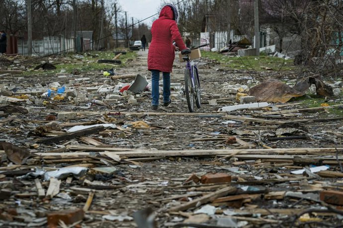 Archivo - April 11, 2022, Chernihiv, Chernihiv, Ukraine: A woman passes with her bicycle over the debris of the destroyed houses by russian shelling in Novoselivka, a village near Chernihiv, Ukraine.