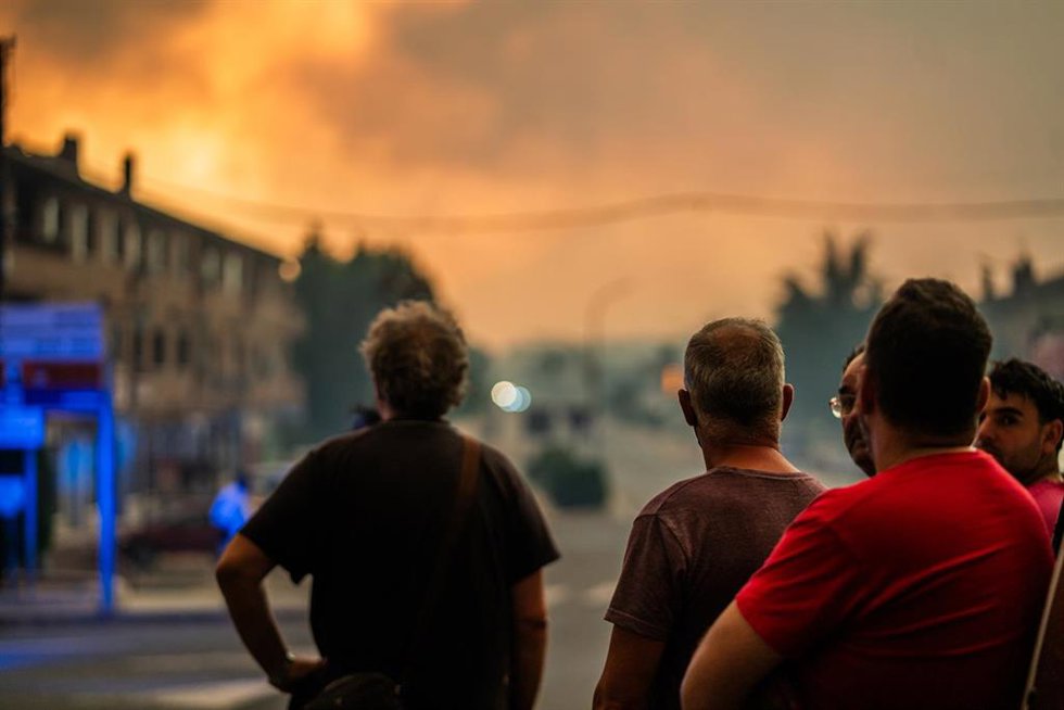 Varias personas observan el fuego durante las labores de extinción del incendio forestal, a 25 de julio de 2026, en La Adrada, Ávila, Castilla y León (España). 