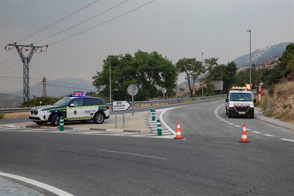 Vehículos de la guardia civil vigilan la carretera cortada durante las labores de extinción del incendio forestal, a 25 de julio de 2026, en Robledo de Chavela, Madrid (España). Durante la noche ha beneficiado el cambio de condiciones meteorológicas, con 