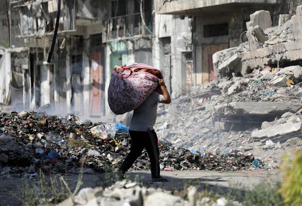 Un palestino desplazado transporta sus pertenencias al abandonar un refugio en el este de Gaza. Imagen de archivo