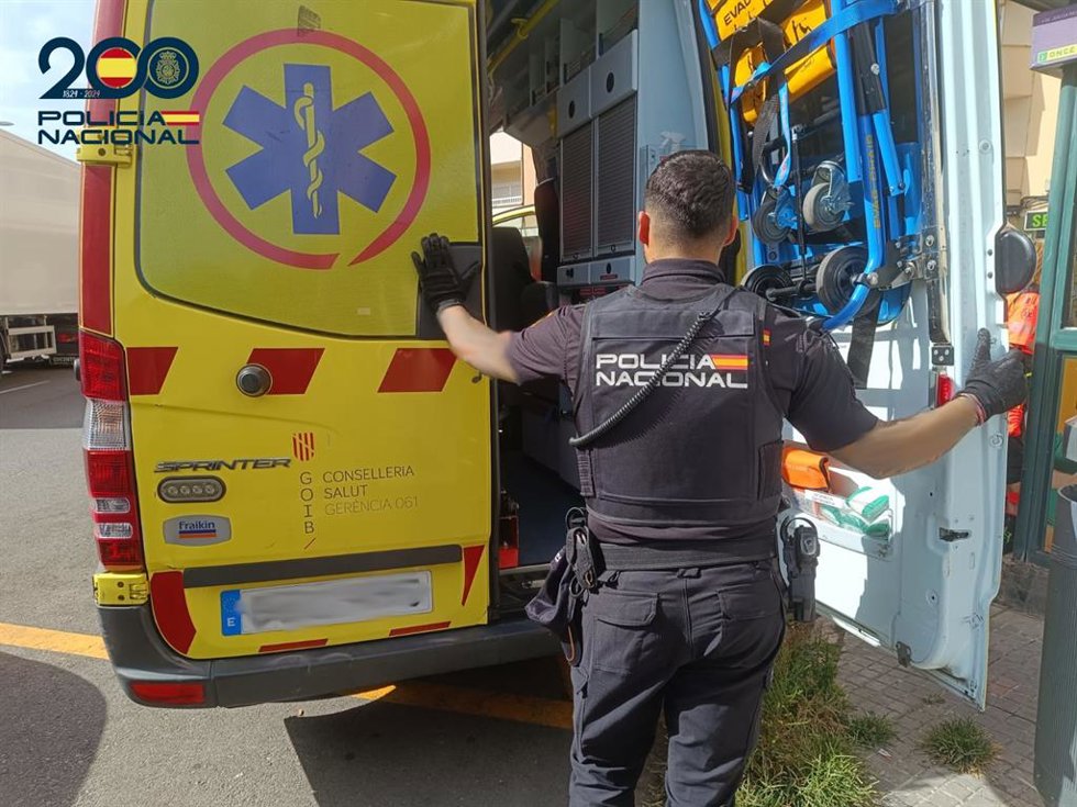 Un agente de la Policía Nacional, junto a una ambulancia.