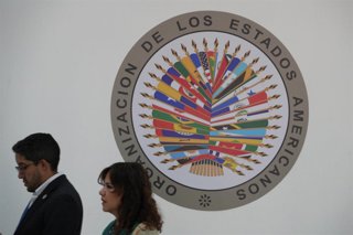 Archivo - Gente pasa junto al logotipo de la Organización de los Estados Americanos (OEA) en Ciudad de Panamá.