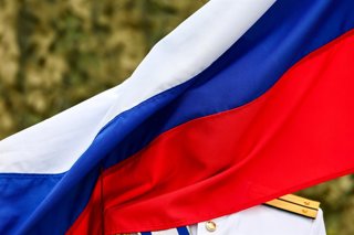 RUSSIA, BALTIYSK - JULY 26, 2026: A Russian Navy officer with a Russian national flag during an event marking the Day of the Russian Navy