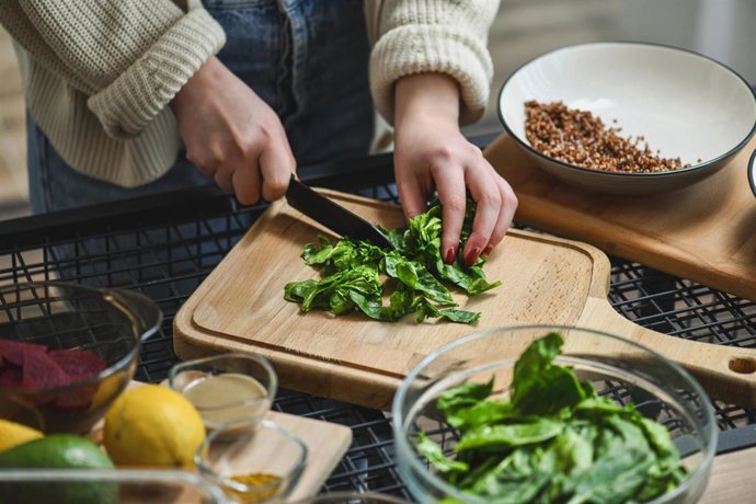 Archivo - Mujer cortando espinaca, alimento rico en betaína.