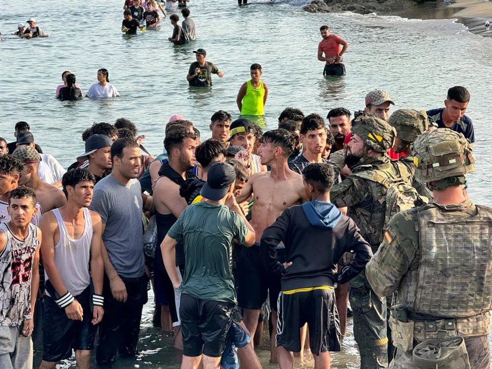 Personas que llegan esta tarde a Ceuta desde Marruecos y se encuentran con los militares que hasta las 20.C0 horas han estado desplegados en la playa