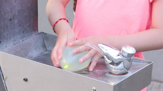 Archivo - Niña jugando con un globo de agua